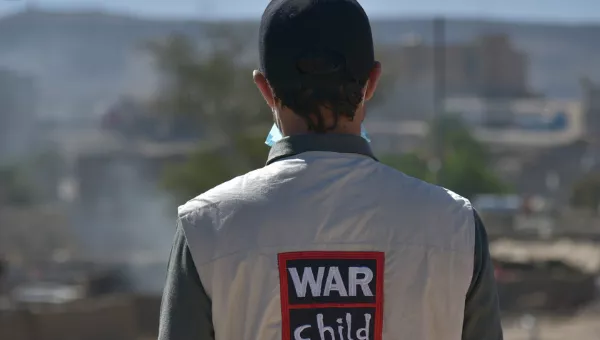 War Child staff member stands with back to camera to show off jacket with War Child logo on back.