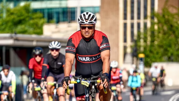 A man riding a bike and wearing a War Child t-shirt.