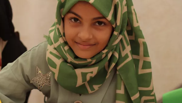 A girl drawing on a piece of paper in a classroom in Yemen.