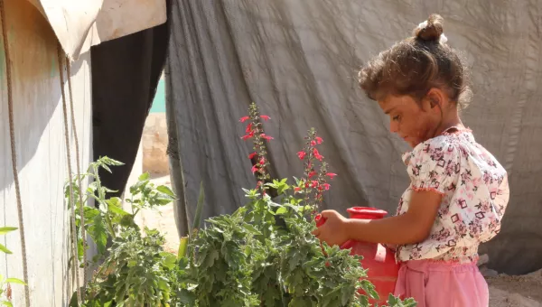 Sama watering flowers in a refugee camp in Syria.