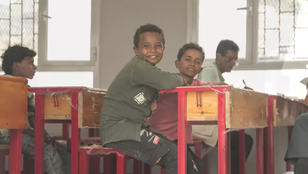 Children sitting at a desk in a classroom in Yemen.
