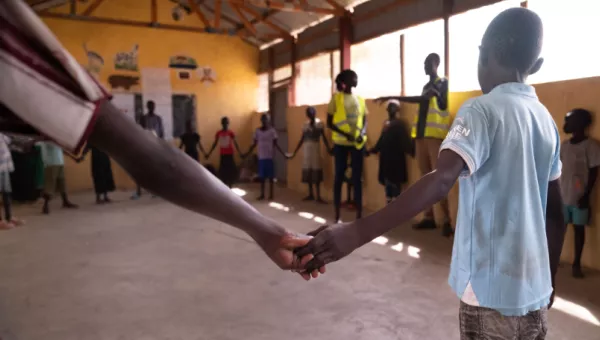 A group of children standing in a circle and holding hands. 