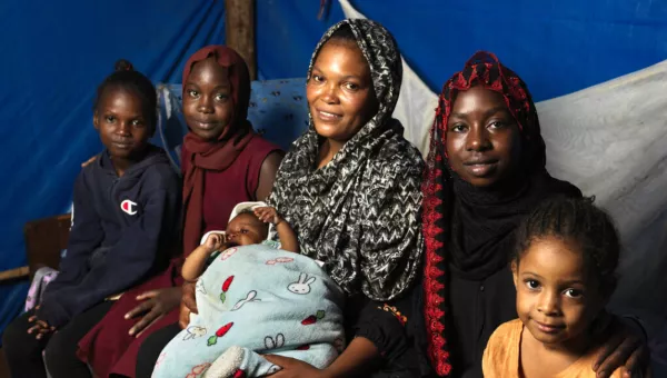 Women and their children sitting together in a tent.