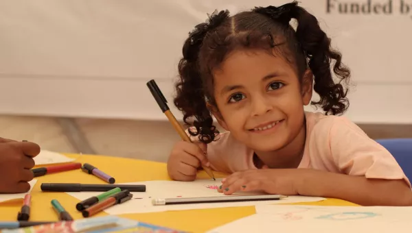 girl smiling at camera and colouring in