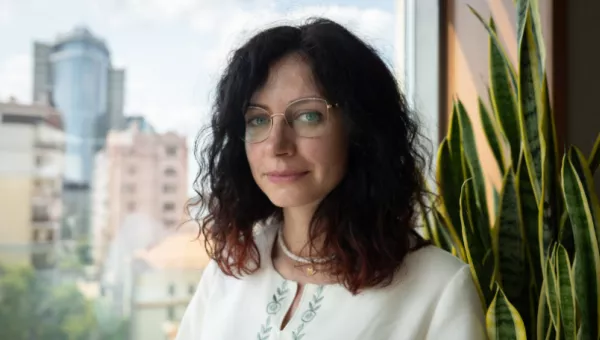 Portrait of Ukrainian women with black curly hair wearing glasses.