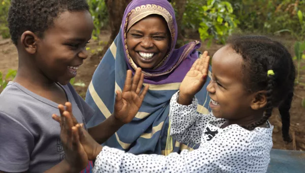 Mother smiling at her two children (girl and boy) playing with each other.