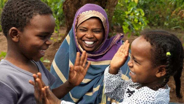 Mother, smiling at her two children (girl and boy) playing together