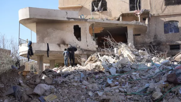 Adult and child standing on top of building rubble.