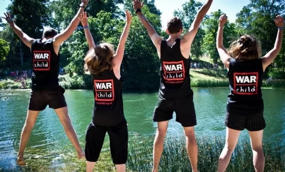 War Child staff jump in the air whilst volunteering at Wilderness Festival.