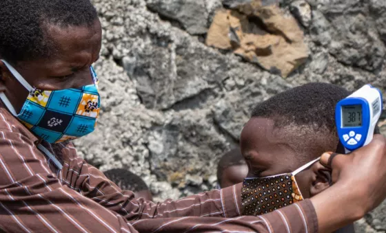 A man helping a boy put his mask on. 