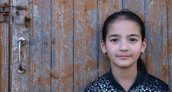 Galina aged 8 in Moldova posing against a wooden door