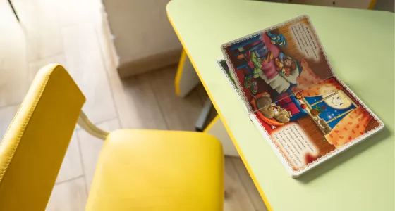 A book on a table with a childs chair.