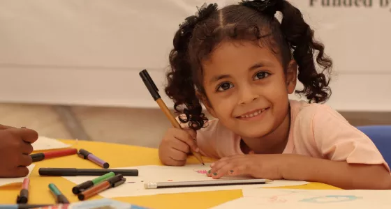 girl smiling at camera and colouring in