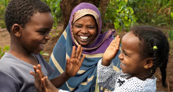 Mother, smiling at her two children (girl and boy) playing together