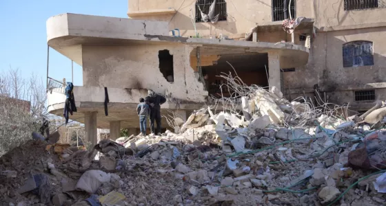 Adult and child standing on top of building rubble.