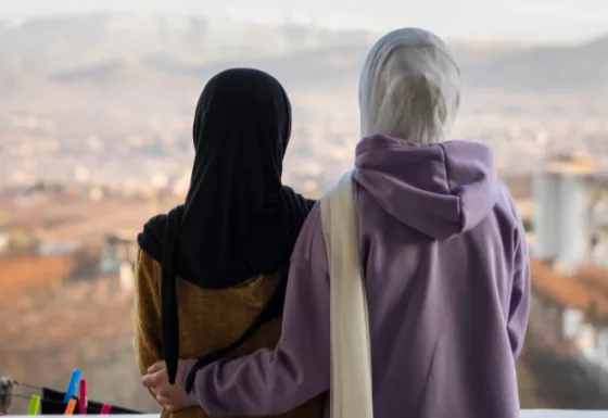 Two young girls wearing hijab looking into the distance