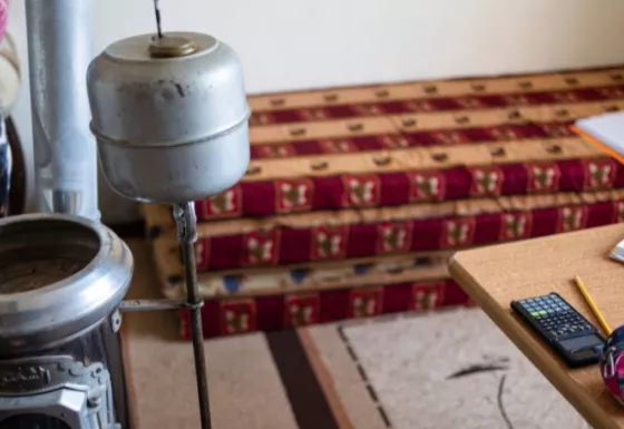 Room with a gas stove, mattress, table with pencils