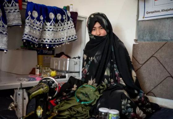 Afghan teen sitting on the ground with her embroidery tools
