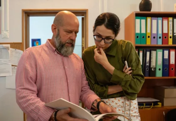 Male and female adult reading a book.