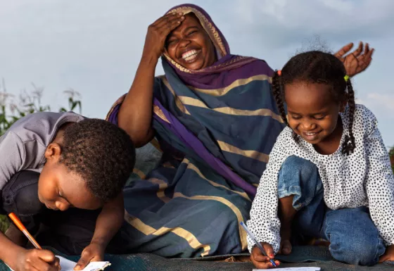 Mother laughing whilst her two children write in a notebook.