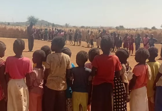 Children standing in a large circle outdoors.